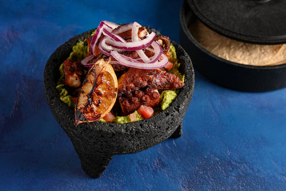Delicious grilled octopus served with fresh guacamole and red onion in a traditional molcajete bowl.