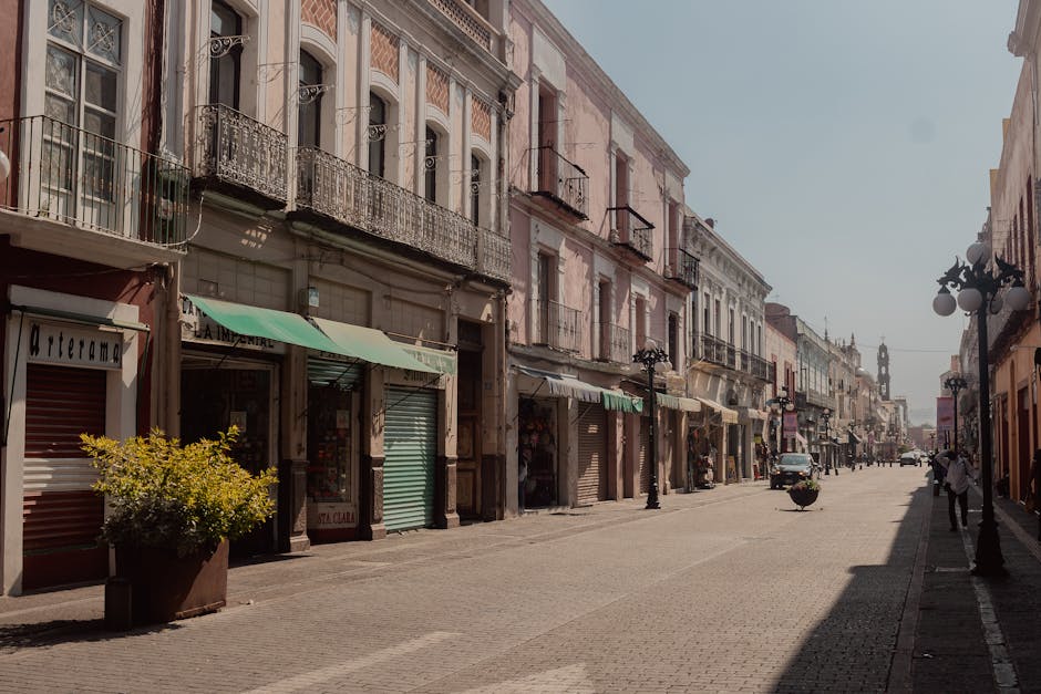 Sunlit urban street with historic buildings in Puebla, Mexico, showcasing vibrant architecture.