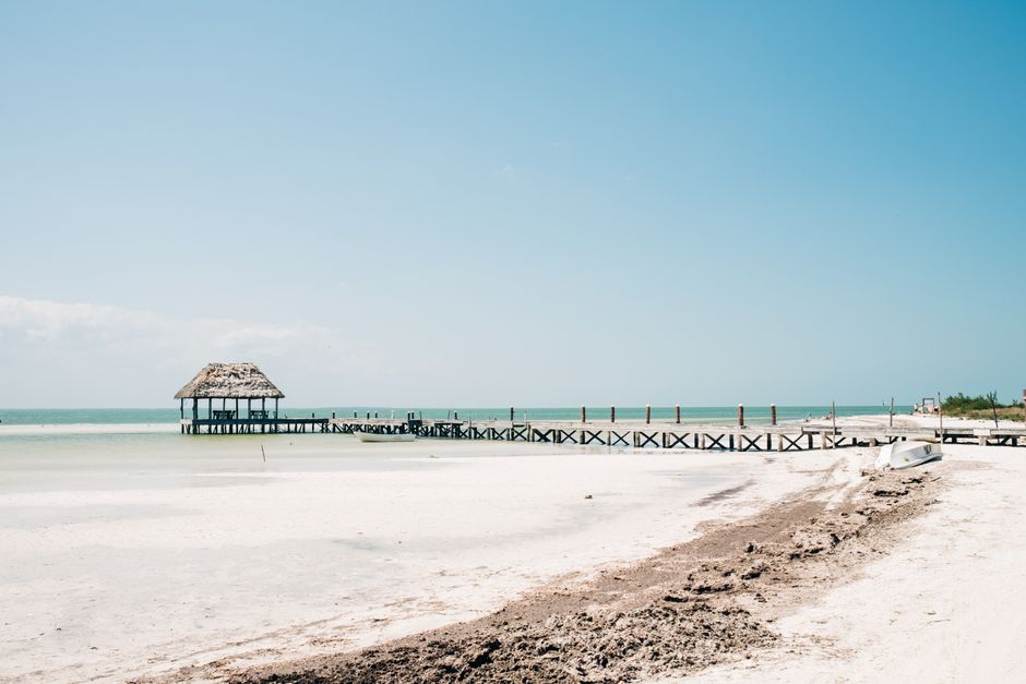 Serene beach scene featuring a rustic pier and tranquil waters in Holbox, Mexico.