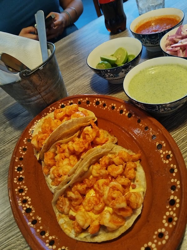 Cliente sosteniendo una hamburguesa con chipotle y papas fritas en Ajua Hamburguesas — vista exterior del local y plato