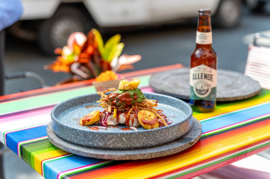 Colorful Mexican cuisine and a bottle of beer displayed on a vibrant table in a CDMX outdoor restaurant scene.