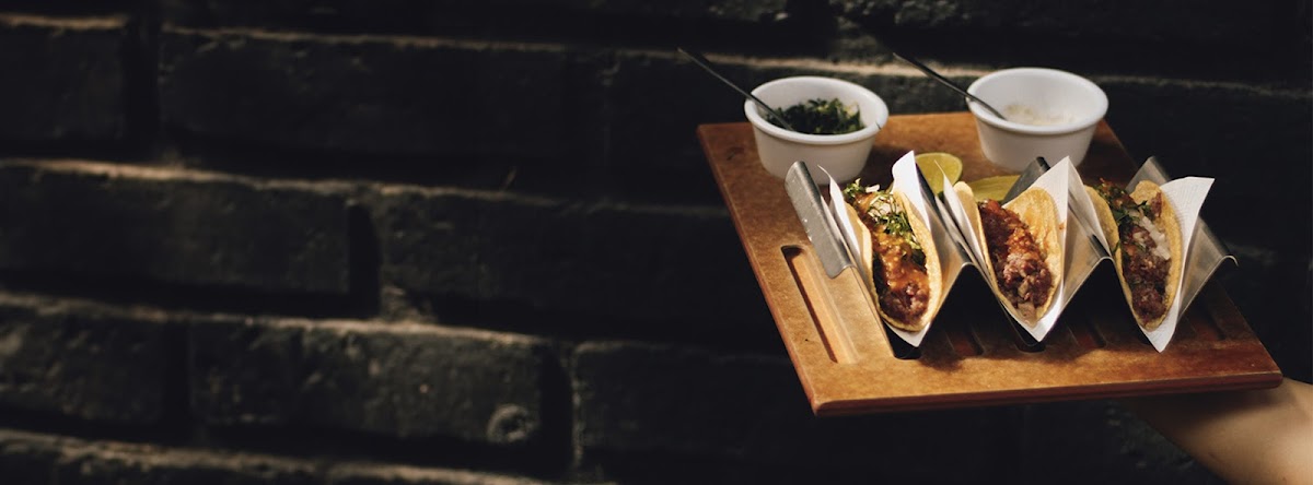 Restaurante Bixa Cocina Auténtica comedor rústico con una mesa de madera, una copa de vino tinto y el plato de cochinita pibil.