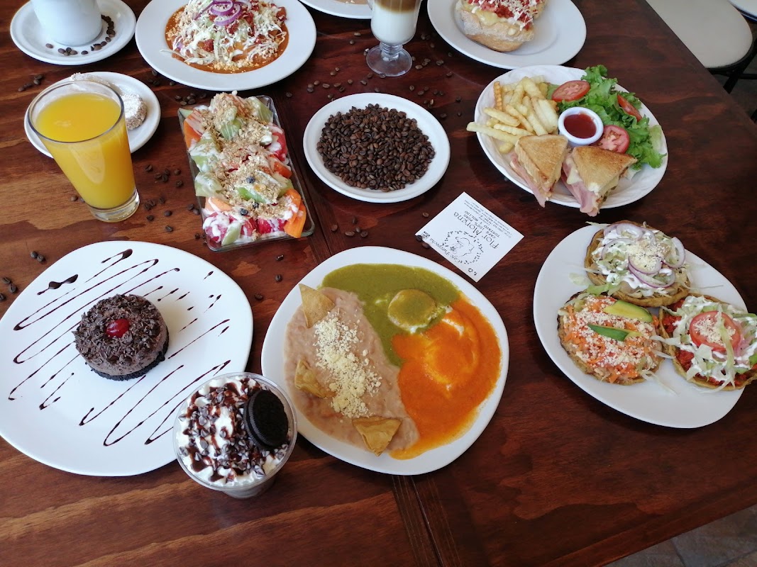 Interior de NANDI CAFÉ mostrando la barra de espresso y una taza de café con espuma, junto a un plato de chilaquiles.