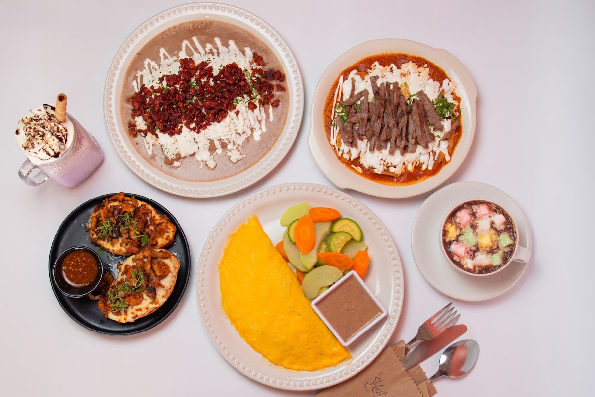 Mesa de desayunos en Hatsö desayuno y almuerzo, con chilaquiles rojos, pan dulce y café humeante