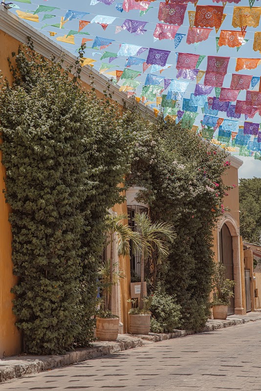 Exterior colorida del Restaurante Kinich Izamal con su fachada amarilla y mesas al aire libre, mostrando un plato de cochinita pibil al centro