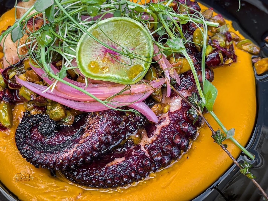 Hambrusia – vista de la terraza al atardecer con tacos de pulpo en primer plano