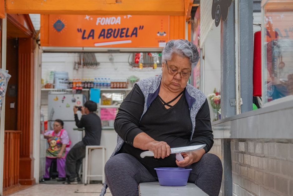 Senior woman preparing food in Guanajuato market fonda 'La Abuela.' Authentic cultural scene.
