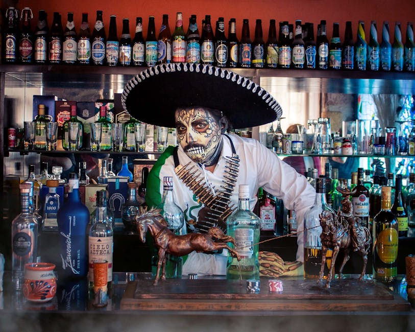 Festive bartender in Day of the Dead attire amidst a colorful bar display, Mexico.
