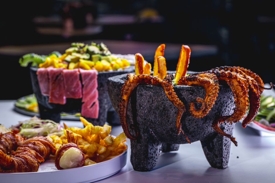 A vibrant dish featuring octopus tentacles and meats in a traditional stone bowl.