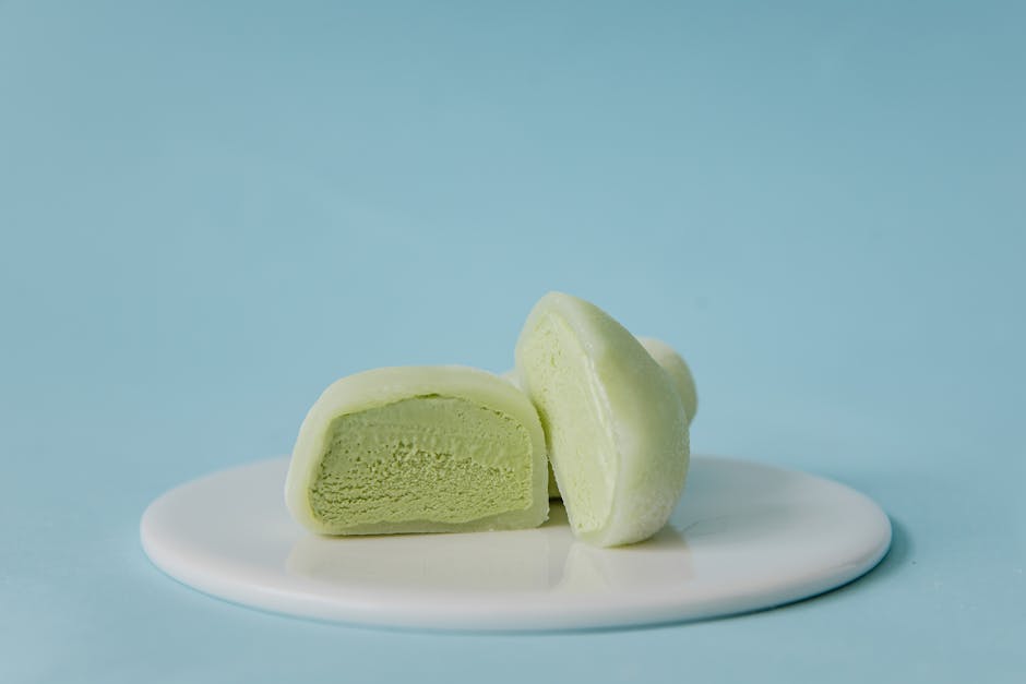 Creamy green tea mochi on a white plate against a pastel blue background.
