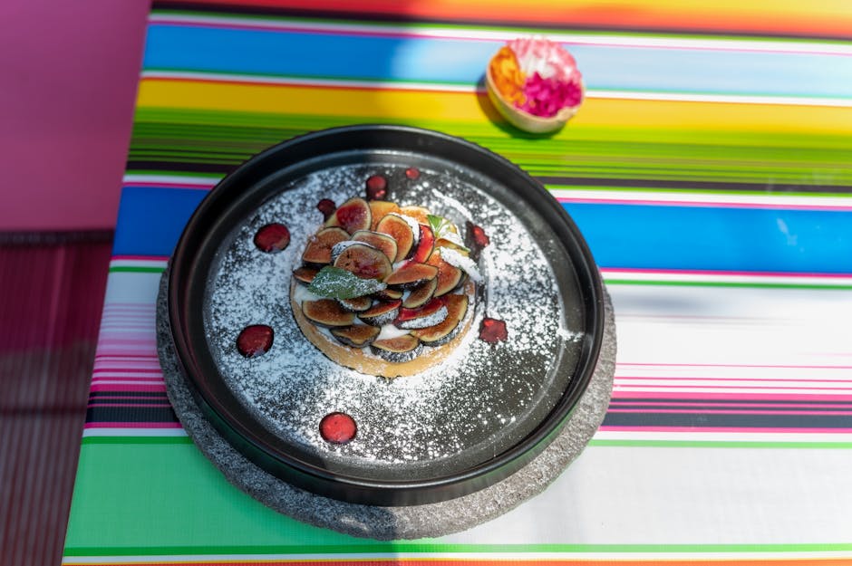 A fig tart dusted with sugar on a vibrant Mexican striped tablecloth, CDMX.