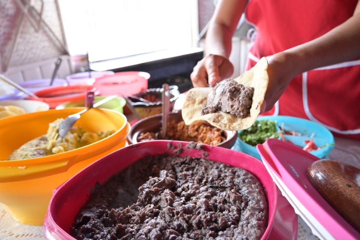 Tacos de carne asada y salsas en Los Porrones — mostrador con tacos y clientes en mesas de madera