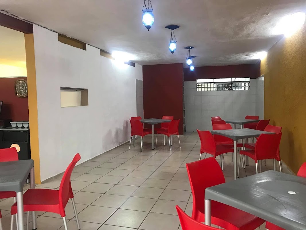Interior del local con chef preparando tacos en la plancha y clientes conversando alrededor