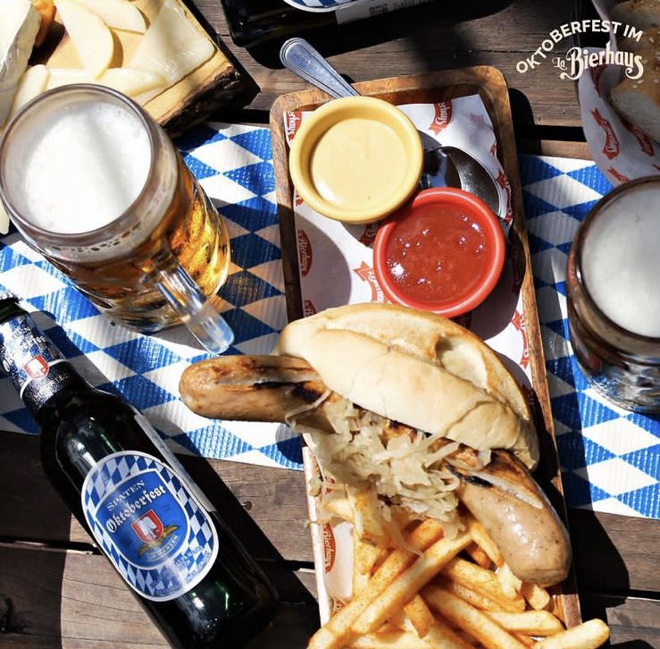 Primer plano del bratwurst con chucrut y una pinta de cerveza en La Bierhaus, mostrando la madera del interior