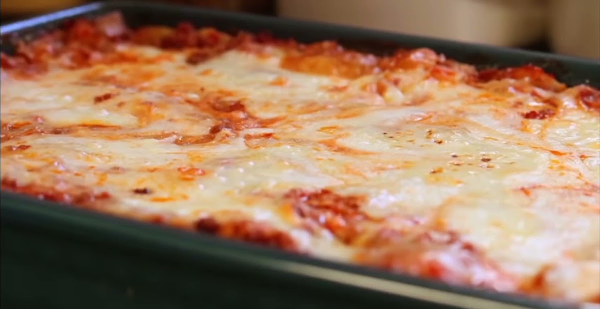 Due Torri – interior con horno de leña y una porción de lasaña recién salida