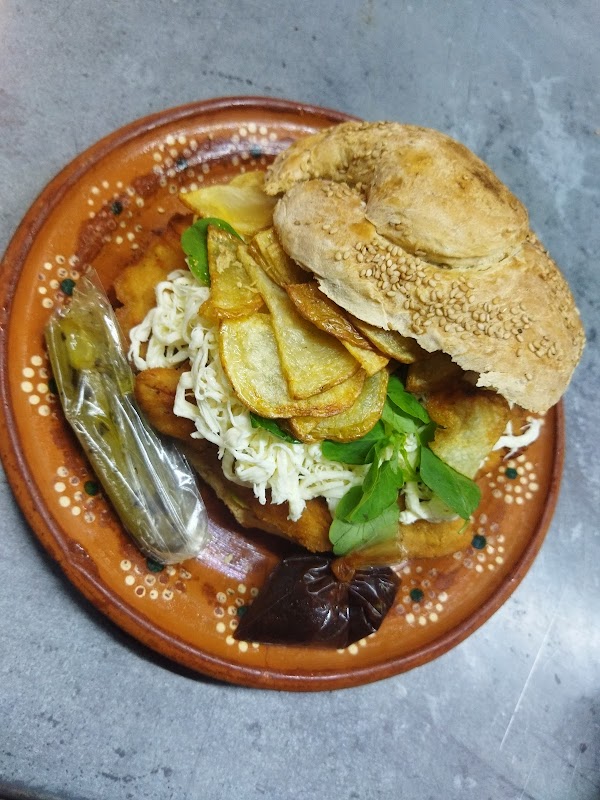Primer plano del huarache de mole en su bandeja, mostrando la salsa brillante y la masa crujiente