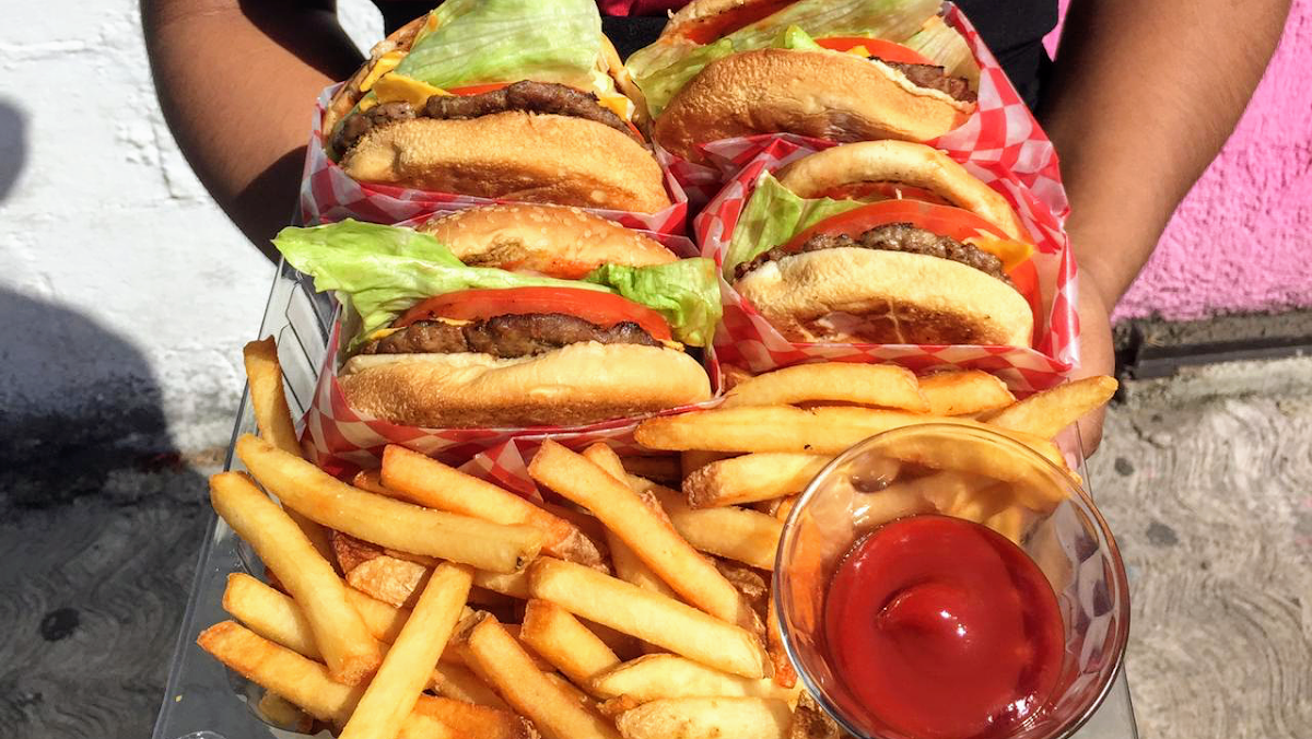 Primer plano de la Horus Classic burger en su plato de cartón, resaltando el queso derretido, la lechuga y la salsa chipotle