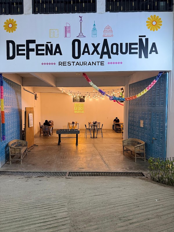 Pizza vegetariana recién salida del horno en Defeña Oaxaqueña, mesa con vasos de refresco y ambiente rústico