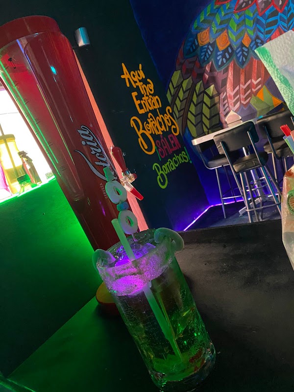 Mural colorido en Las De Harry's con gente tomando cerveza artesanal en una mesa exterior