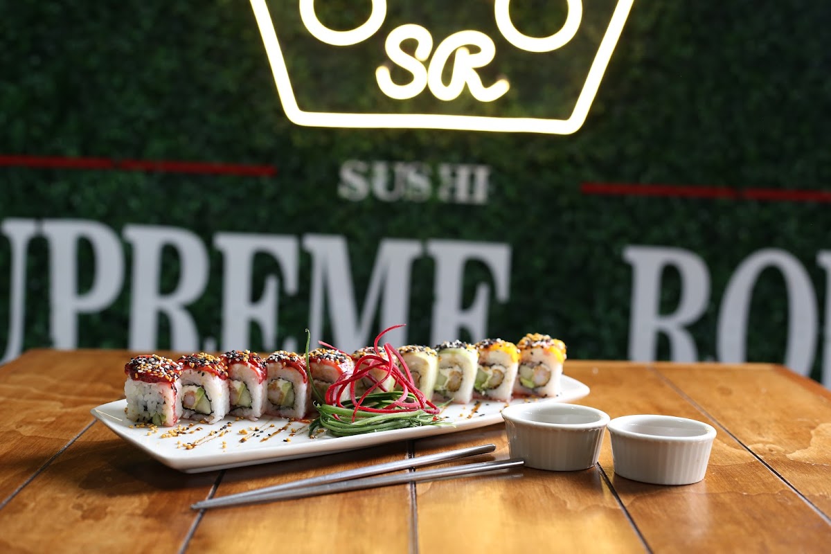 Supreme Roll mostranto una bandeja de sushi rolls coloridos y una taza de sopa miso, enfoque en la frescura