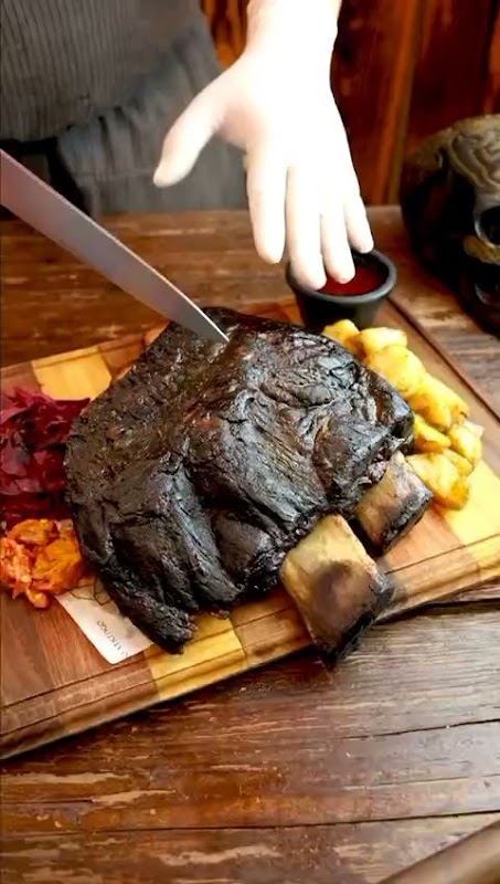 Kød Rustic Deli mostranto un sándwich de carne curada y una cerveza artesanal en la barra de madera