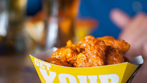 Pantalla gigante mostrando un partido y alitas en Buffalo Wild Wings