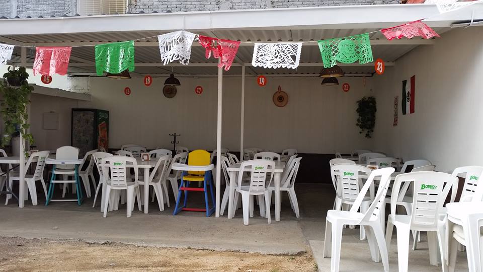 Interior del local con el chef preparando tortillas a mano y el mostrador lleno de salsas y tacos