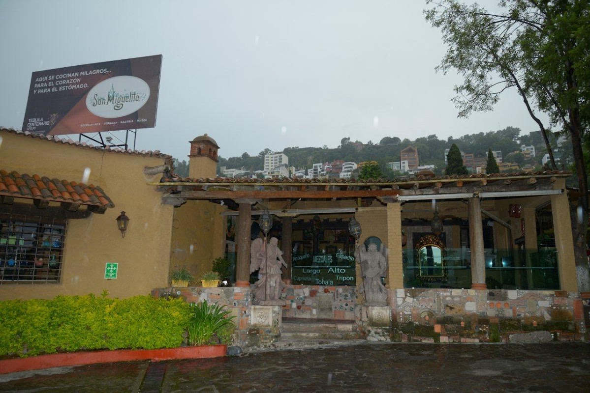 Restaurante Caracuaro – plato de cecina y totopos sobre mesa rústica, con botella de mezcal al fondo