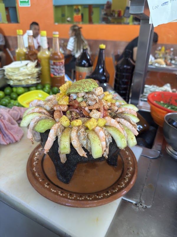 Barrita de Mar Satélite – tacos de pulpo servidos en plato de cartón, barra llena de clientes