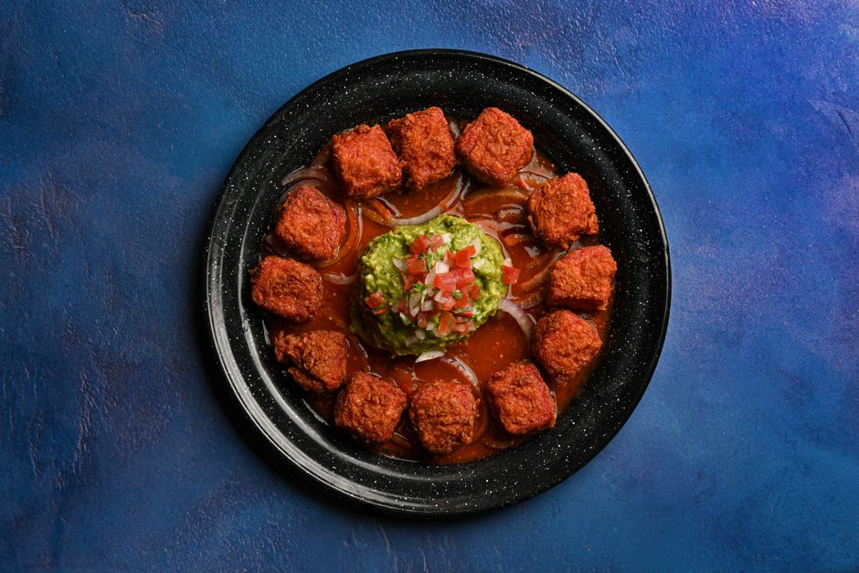 Delicious Mexican meatballs served with guacamole over a vibrant blue background.