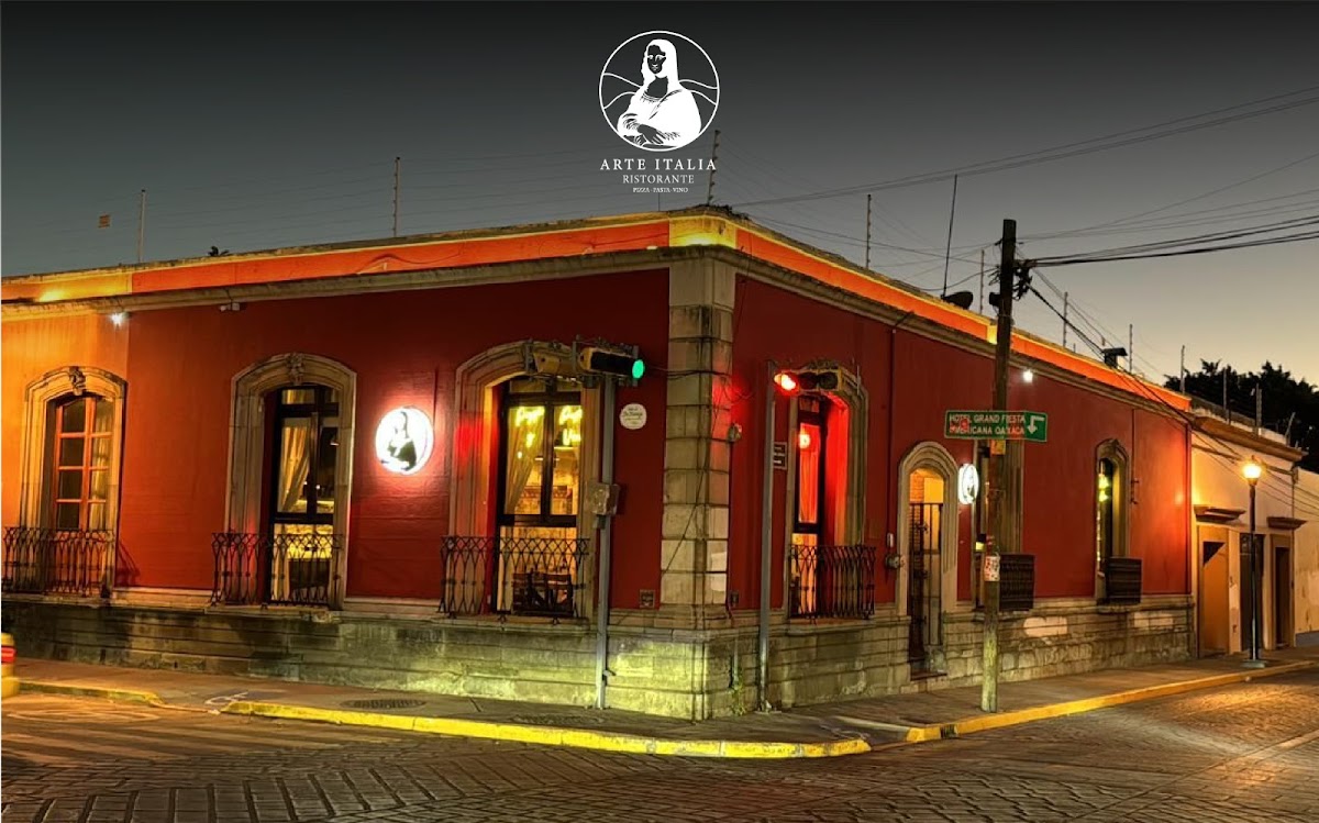 Fachada de Italianni's Oaxaca con su letrero iluminado y mesas al aire libre, mostrando clientes disfrutando de una pizza al horno