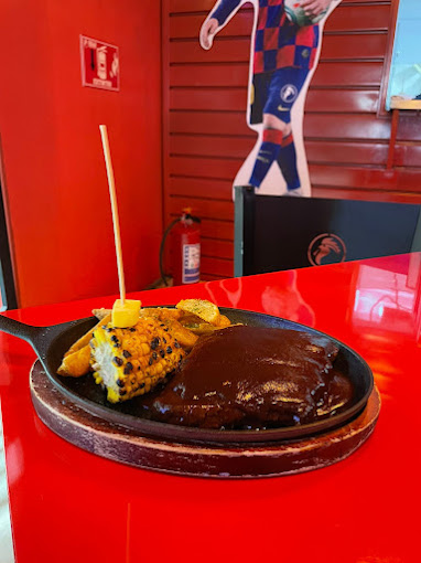 Hamburguesa jugosa de Gallo Cervecero SportsBar con papas crujientes y una michelada al lado