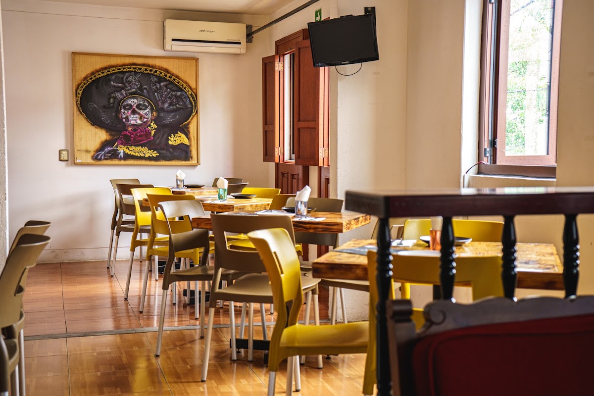 Interior de Totopo Güero con mesas de madera, barra de mezcal y clientes disfrutando, captura la atmósfera cálida del lugar