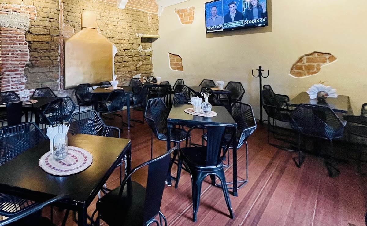 Interior de ALAMBIQUE con escenario de rock, barra de cobre y clientes disfrutando mezcal — captura la atmósfera nocturna