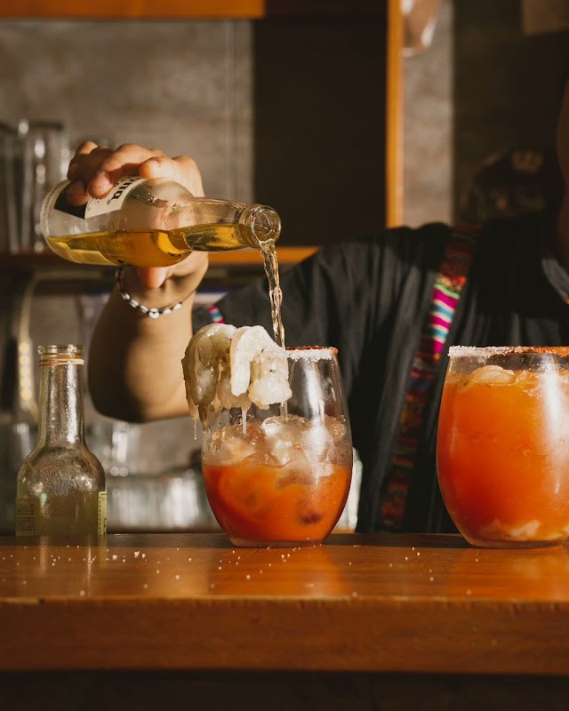 Barra con copas de mezcal y margarita de tamarindo en ALAMBIQUE, ambiente de música en vivo