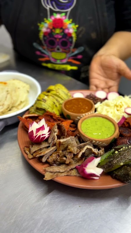 Tlayuda de tasajo en ALAMBIQUE — plato servido en tabla de madera, mostrando tortilla crujiente, tasajo dorado, lechuga, rábanos y queso