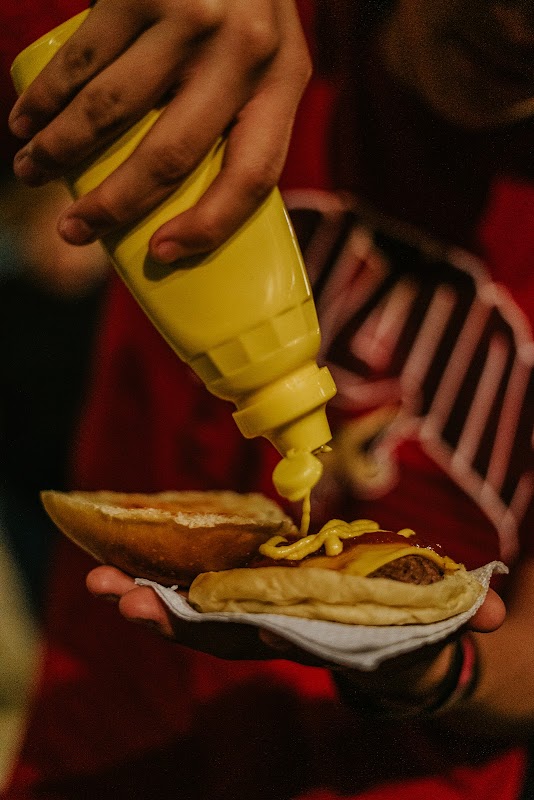 Primer plano de la Jesus Burger con queso fundido, cebolla caramelizada y salsa chipotle, acompañada de papas fritas crujientes