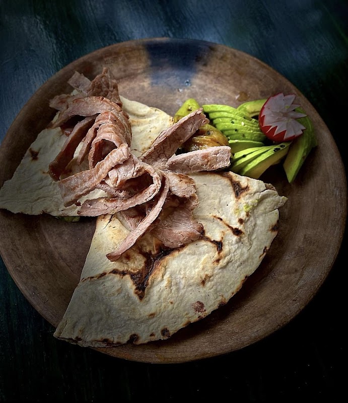 Tlayuda de cochinita pibil en El Empedrado, mostrando la tortilla crujiente, carne deshebrada, salsa de habanero y queso fresco