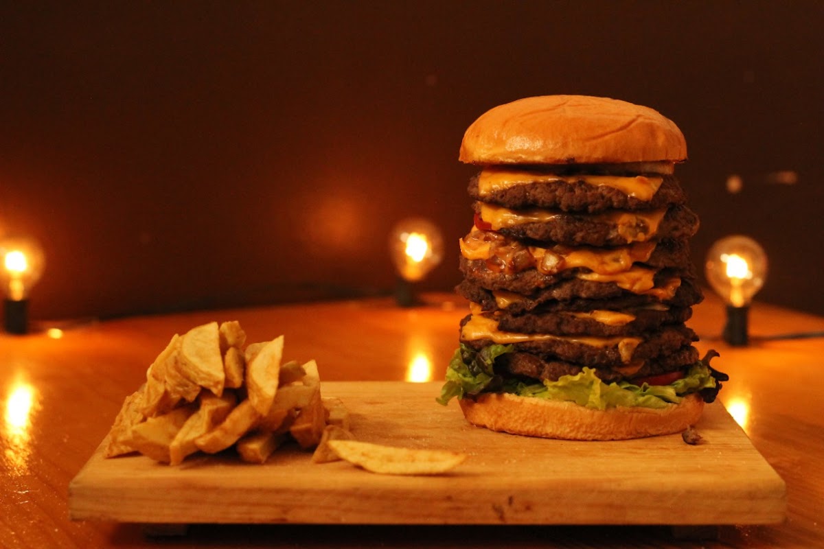 Hamburguesa con pan de waffle y papas fritas en una tabla de madera, mostrando la combinación de dulce y picante en Chucho Burger