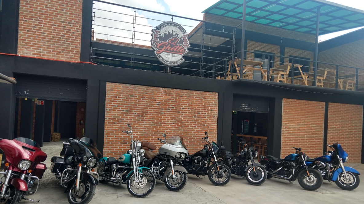 Mesa de El Ghetto Biker Club Garage con una quesabirria humeante, birriamen en cuenco y decoración de motos vintage