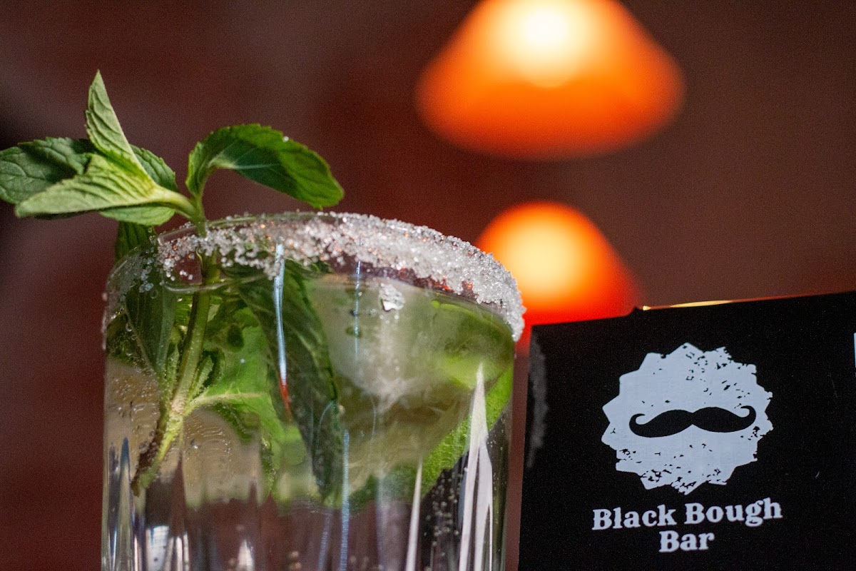 Interior de Black Bough Bar con luces tenues, barra de madera y una tabla de tacos acompañada de una cerveza artesanal