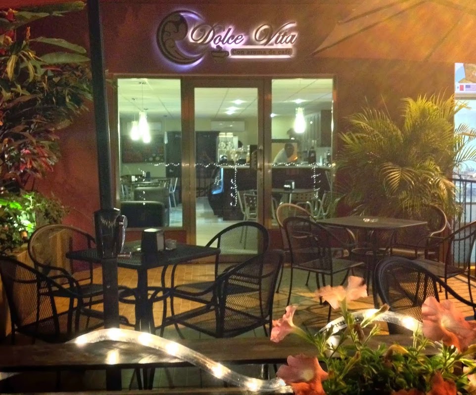 Exterior de Dolce Vita Coffee con su letrero y mesas al aire libre, mostrando la fachada en la carretera Dos Bocas