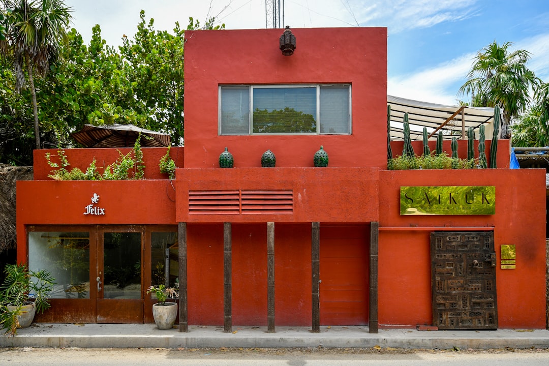 A bright red building with wooden columns and plants.