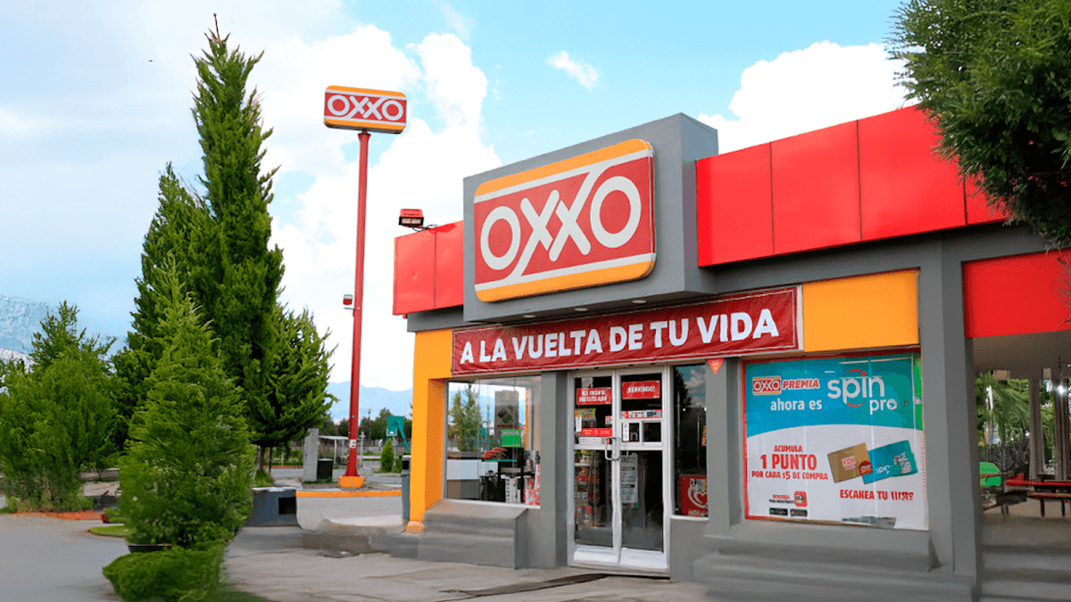 OXXO Penón Blanco DGO – storefront at night with illuminated signage, showing a shopper picking up a snack from the aisle