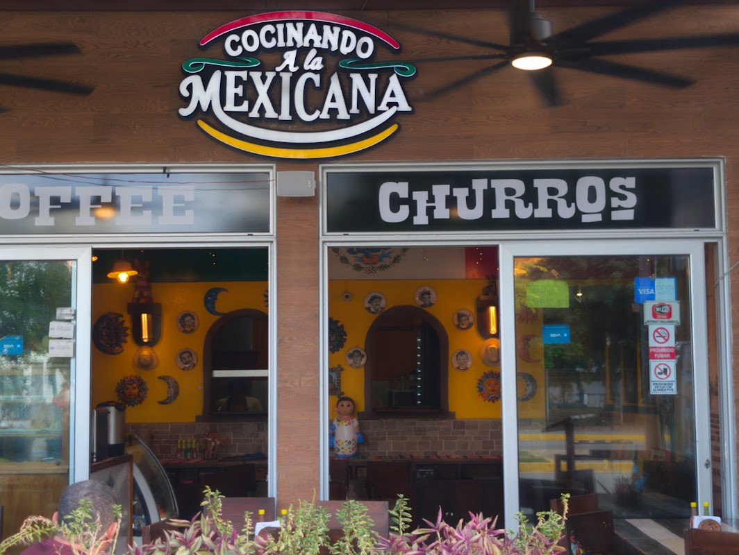 Tacos de pastor y churros en COCINANDO A la MEXICANA, mostrados en el mostrador con la cocina abierta de fondo