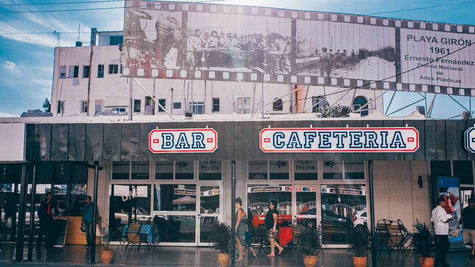 Street view of a bar cafeteria in Havana, Cuba with people walking by.