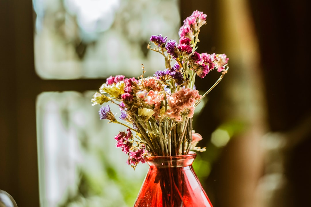 pink and yellow flowers in red glass vase