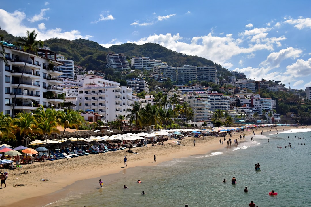 Beach with umbrellas and people, city on hill