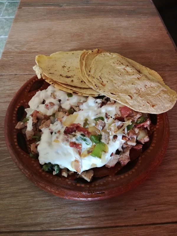 Carnitas recién cocidas en Carnitas Carmelo, mostradas en una tabla de madera con tortillas y limón