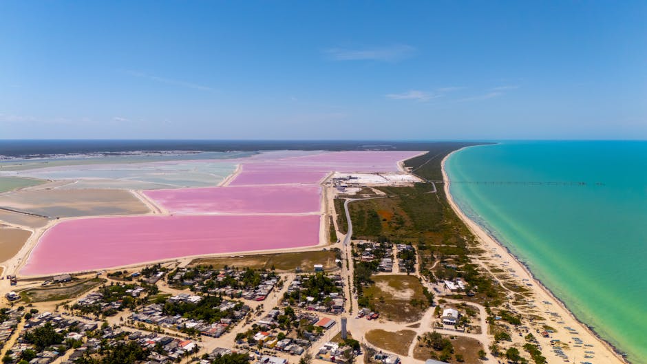 Stunning aerial view of vibrant pink salt ponds and turquoise sea in colorful Mexican landscape.
